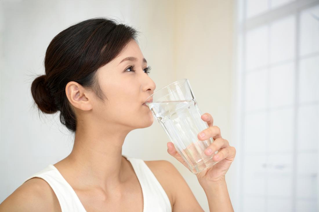 Woman drinking water which is a home remedy for gout