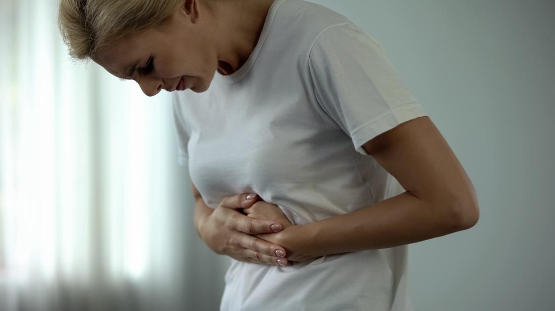 woman holding upper stomach in pain