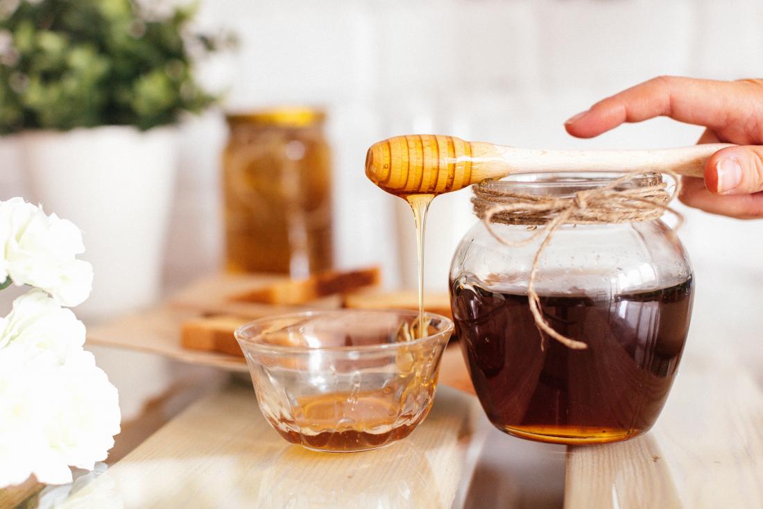 Raw honey in jar on wooden table