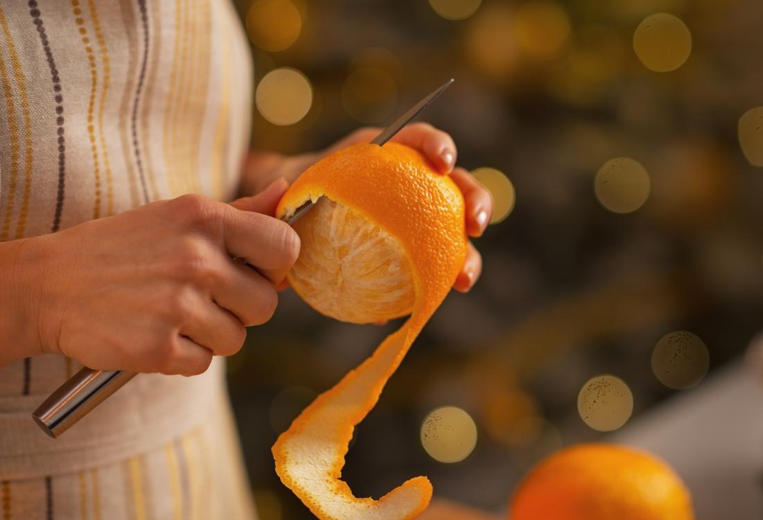 woman peeling an orange with a knife