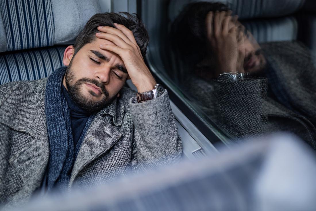 man with headache or migraine holds head leaning against the vehicle window