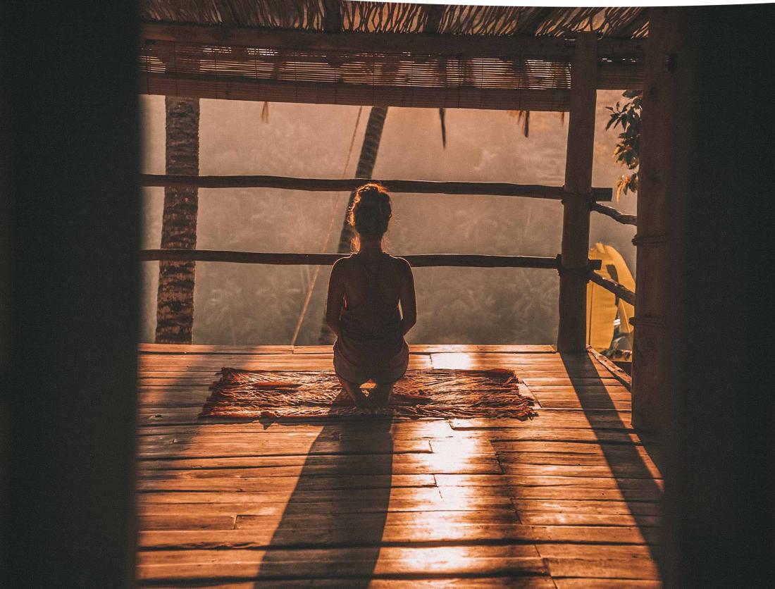 person meditating at sunset
