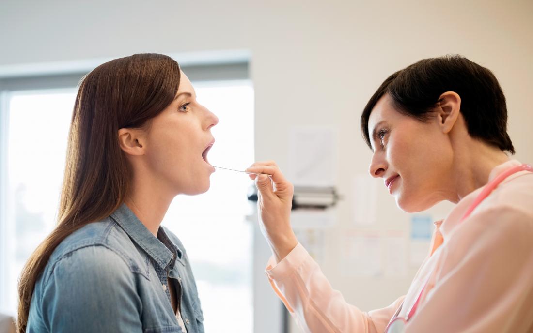 a doctor looking in a womans mouth to see if she has a black hairy tongue. 
