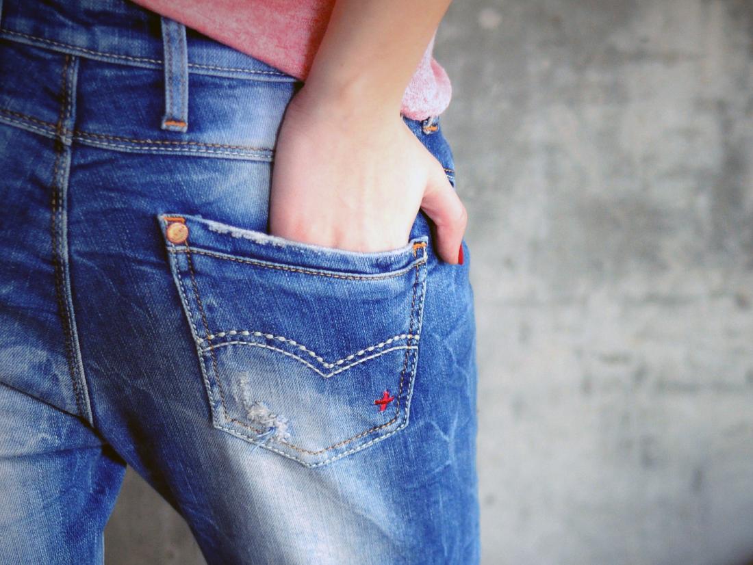 a woman with her hand in her back pocket because her bum is itchy from a anal yeast infection. 