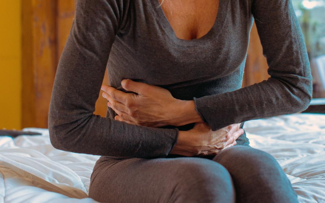 a woman holding her stomach and wondering Can nausea cause constipation