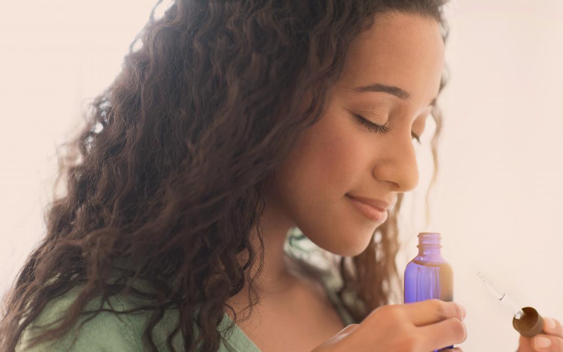 a woman smelling neem oil that she is going to use for her skin