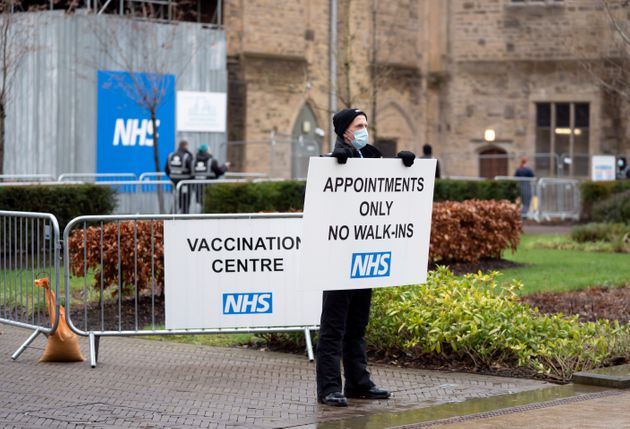 A security guard holds a sign at Blackburn Cathedral, which is being used as a mass vaccination center...