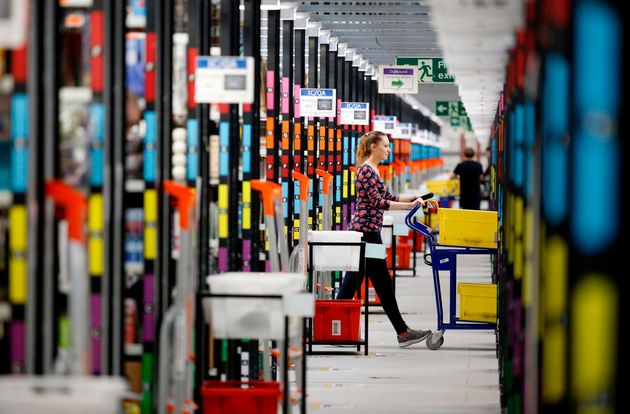 A 'picker' worker collects items from storage shelves as she collates a customer order inside an Amazon.co.uk...