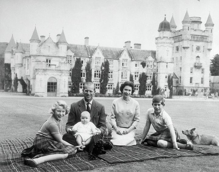 Baby Prince Andrew perches on Prince Philip's lap during a picnic on the grounds of Balmoral Castle. Also pictured are Queen Elizabeth, Prince Charles, and Princess Anne