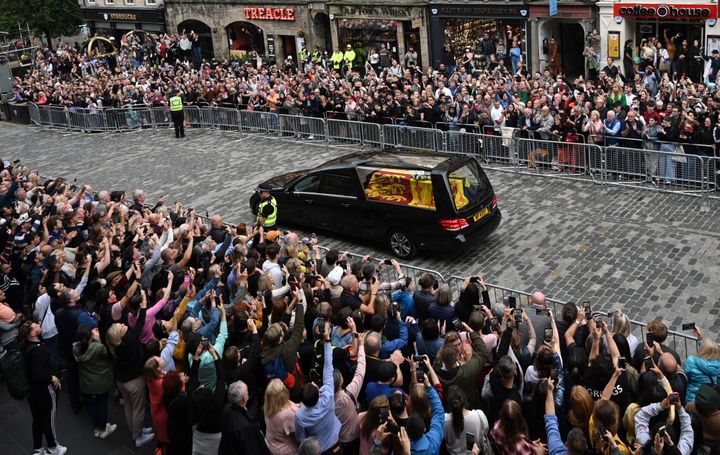 Members of the public watch the hearse carrying the coffin of Queen Elizabeth II as it is driven through Edinburgh.