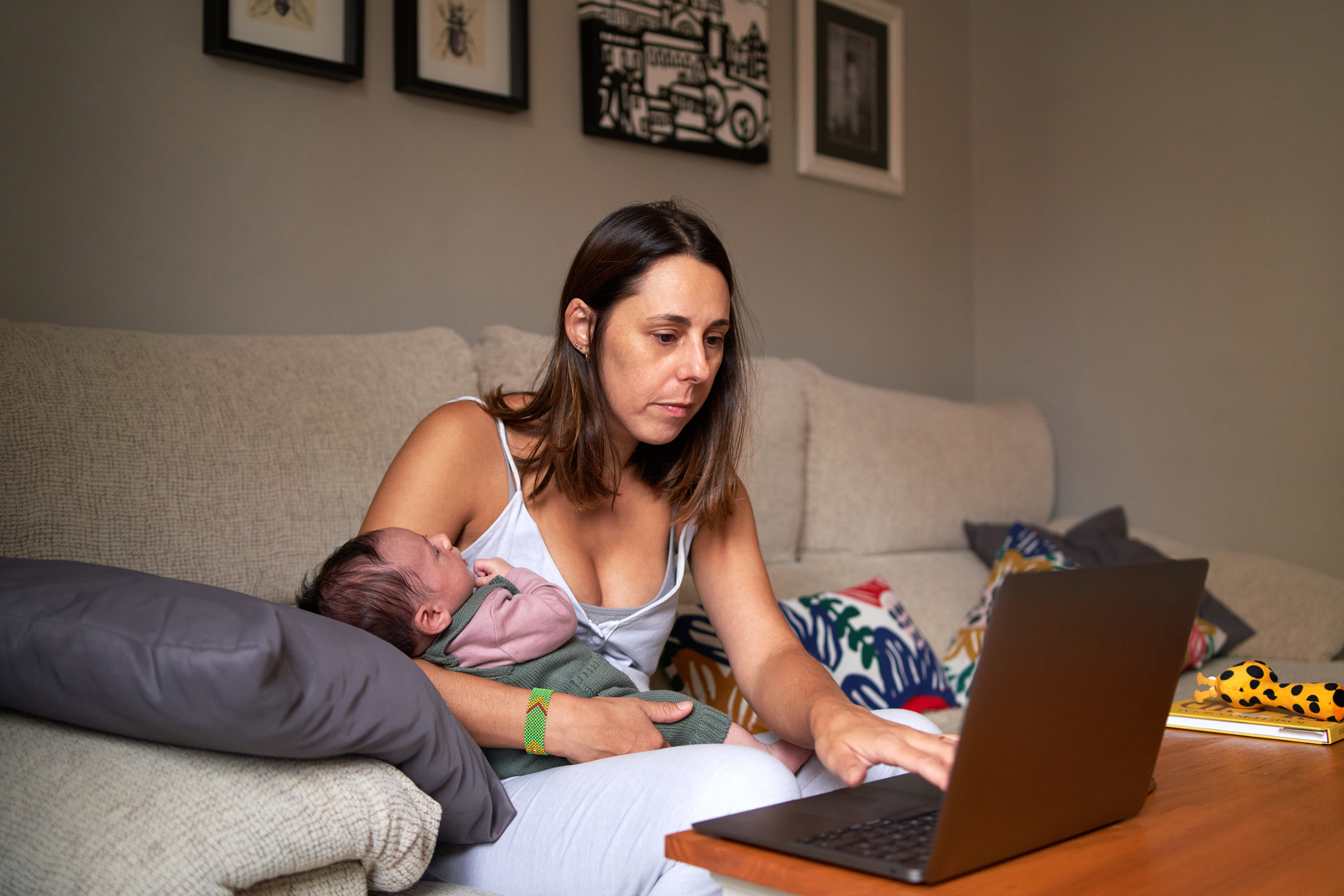 Portrait of a stressed woman tries to work from home with baby in arms