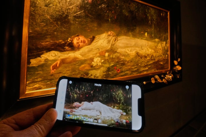 Taylor Swift's video for The Fate Of Ophelia is displayed on a mobile phone in a museum showing a painting by Art Nouveau painter Friedrich Heyser of the character